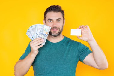 Adam sarı stüdyonun arka planına para koydu. Dolar banknotları olan zengin adamın portresi. Dolar banknotları olan başarılı bir adam. Zengin milyoner.