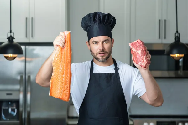 現代のキッチンで男 一人で健康的な食べ物を準備 魚や肉を調理 サーモンと牛肉 家のキッチンで新鮮な魚や肉 サーモンや牛肉を準備しているハンサムな男 — ストック写真