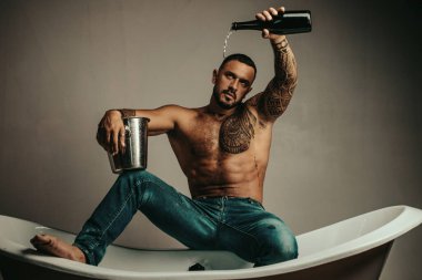 Gece partisi. Satın alma gayrimenkul kutlayın. Lüks hayatı kutlayın. Başarıyı kutlayın. Lüks küvette şampanya kutlaması. Yakışıklı çekici adam dövmeli vücut pahalı şampanya içme.