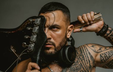 Gitar çal. Göğüs kasları, altılı paket. Elektro gitar. Müzik festivali. Sahne ve bando enstrümanları. Güçlü, kaslı, kaslı adam. Müzik konsepti