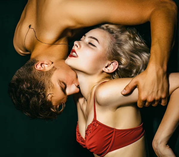 Man kissing woman to neck. Couple In Love. Beautiful straight female body in red bra with muscular man. Beautiful playful woman want kiss man. Casual style