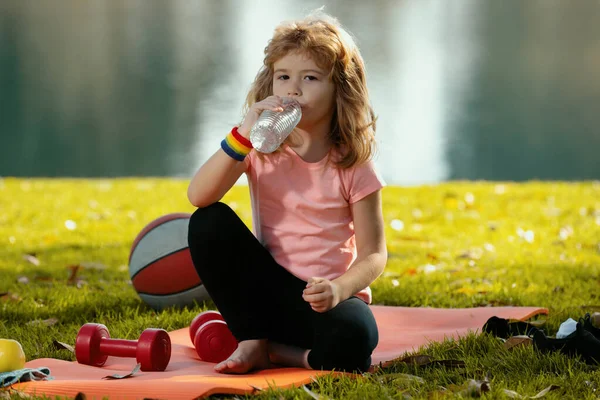 Çocuk sağlıklı yiyecekler yiyor, egzersizden sonra su içiyor. Fitness, sağlıklı meyveler ve aktif yaşam tarzları. Çocuk sporu kavramı