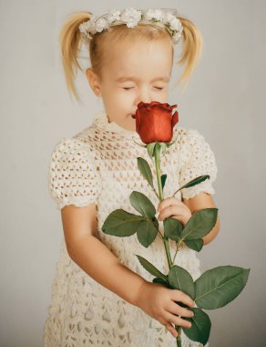 Aşk hediyesi. Çocuklar Günü 'nde. Kırmızı güllü küçük bir çocuk. Mutlu çocukluk. Sevgililer Günü. Romantik randevu. Eski moda elbiseli küçük kız. Güzellik. Eski tarz. Doğum günün kutlu olsun. Düğün. Ne harika bir koku..