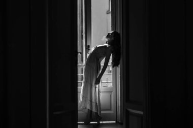 Kadın sabah balkonun yanında buluşuyor. O mutlu dans eder. Kız gece kıyafeti giymiş. Balkonun yanında duran genç bir kadın. Rahatlama ve rahatlama günü