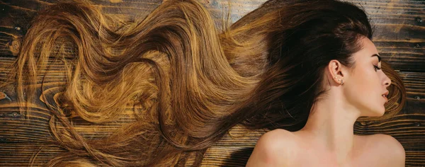 与卷曲的发型模型 美发沙龙概念 护理和头发产品 洗发水和护发素 专业护理 令人惊叹的美丽 长头发的木背景的女人 华丽的头发 — 图库照片