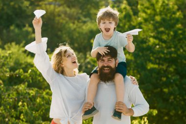Baba, anne ve oğul kamp yapıyor. Baba, anne ve oğlu gökyüzü arka planında oynuyorlar. Mutlu çocuk ve ebeveynler oyuncak kanatlarla oynuyor yaz gökyüzü arka planına karşı