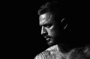 Acımasız bir adam, yakışıklı erkek modelin ciddi yüzü, erkek gücü kavramı ve güçlü. Siyahların üzerinde ciddi profili olan bir adamın yakın plan portresi.