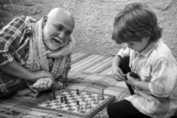 stock image Childhood. Senior man teaching his grandson to play chess. Kid Playing Chess. Grandfather and grandson concept