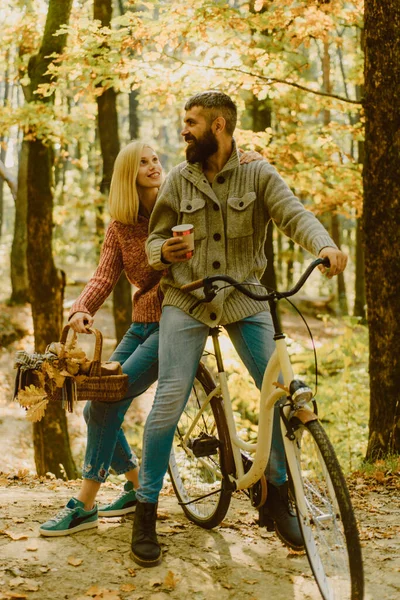 Bearded man and woman relaxing in autumn forest. Romantic couple on date. Date and love. Couple in love ride bicycle together in forest park. Ideas for perfect autumn date. Romantic date with bicycle.