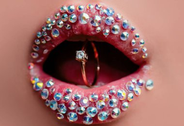 Ağzında pırlanta olan yüzük. Yüzüklü kırmızı dudaklar. Güzel kadınların dudaklarına yakın çekim. Altın yüzüklü bir ağız. Mücevher aksesuarları. Elmas takılı dudaklar