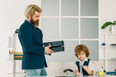 Küçük patron ofiste. Oğul, babaya ofiste yardım ediyor. Ofis çalışanları. Genç iş arkadaşları modern çalışma ofisinde harika iş görüşmeleri yapıyorlar.
