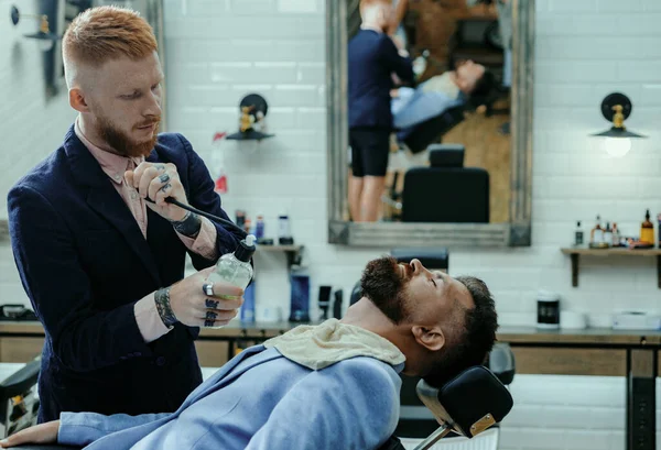 stock image Vintage barber shop shaving. Bearded man. Beard care. Master hairdresser does hairstyle and style with scissors and comb. Hairdresser makes hairstyle man with beard. Brutal guy in modern Barber Shop