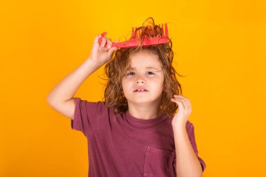 Çocuk berberi. Sarışın, uzun saçlı çocuk saçlarını taramaya çalışıyor. Taraklı bir saç portresi.