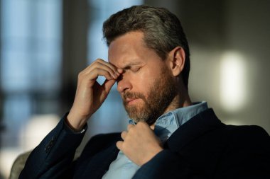 Yorgun adamın korkunç bir baş ağrısı var. Bitkin, sağlıksız hisseden, baş ağrısı hastalığına üzülen bir adam. Stresli orta yaşlı bir adamın baş ağrısı olan portresi. Migren ve baş ağrısı konsepti