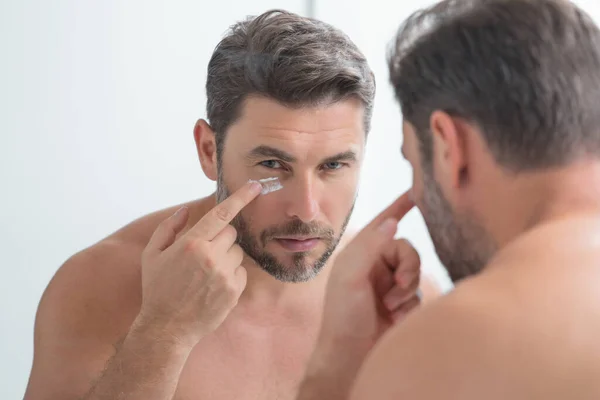 閉じて 男性のしわ 肌のしわに触れるブルネットの男の肖像画 鏡の前にタッチしわを持つ中年の男 老化した皮膚 40代男性化粧品皮膚治療 しわのある男性の顔 — ストック写真