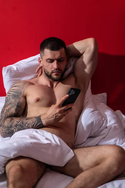 Σέξι Άντρας Ξαπλωμένος Στο Κρεβάτι Χρησιμοποιώντας Κινητό Του Μυώδες Σώμα — Φωτογραφία Αρχείου