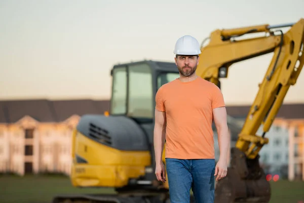 Construction man with excavator at industrial site. Worker in helmet build with bulldozer. Engineer work with builder contractor in hardhat. Excavation foreman with tractor. Workman with excavator