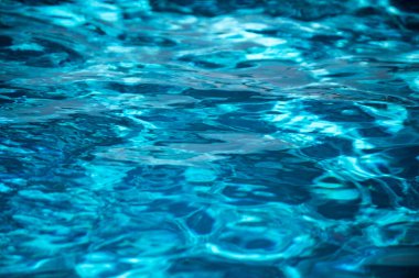 Su arka planı, dalgalanma dalgaları. Mavi yüzme havuzu deseni. Deniz yüzeyi. Yüzme havuzunda su ve güneş yansıması. Kopyalama alanı olan pankart