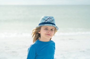 Dışarıdaki sevimli çocuğun hayat tarzı portresi. Yazlık çocukların açık hava portresi. Deniz kıyısında güneş gözlüğü ve şapka takan küçük bir çocuk. Yaz tatilindeki çocuk.
