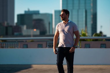 Büyük şehirde kendine güvenen yakışıklı bir adamın portresi. Sokakta poz veren sıradan giyinmiş seksi bir adam. Şehir yaşam tarzında başarılı bir erkek model. Kafkasyalı orta yaşlı adam dışarıda.