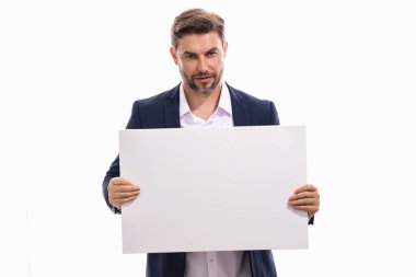 Boş afişi olan ciddi bir adam stüdyo arka planında yalnız poz veriyor. Elinde boş poster tutan çekici bir adamın portresi. Boş poster gösteren bir adam. Erkek panosu, ilan panosu.