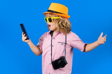 Çocuk gezgin. Sevimli çocuk fotoğraf makinesi ve telefonla fotoğraf çekiyor. Gezgin çocuk telefonda sohbet ediyor. Tatil seyahat yaşam tarzı