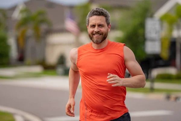 Running man sprinting workout outdoor. Fit athlete man running on american neighborhood