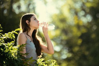 Şişeden su içen sağlıklı bir kadın. Susuz kalma konsepti. Susuz kalmış. Doğayla birlik, açık hava