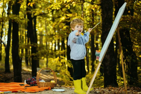 Little boy painting picture in nature. Art and self expression. Talent development. Painting skills. Rest and hobby concept. Painter with easel and canvas. Painter artist forest. Painting school.