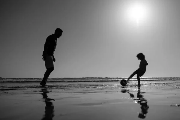 父と息子は夏休みにビーチでサッカーやサッカーをする — ストック写真