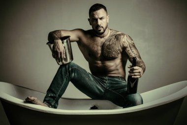 bekar adam şişeden şampanya içer. buz kovası ile soğuk alkol. acımasız sporcu gövde. spor ve fitness, sağlık. dövme adam seksi abs. erkek yalnızlığı. atletik vücutile kas maço adam.