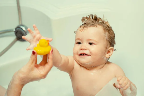 小孩在浴缸里洗澡有趣而快乐的婴儿在浴缸里用水和泡沫洗澡 孩子的卫生 带着玩具鸭在浴室里笑孩子 — 图库照片