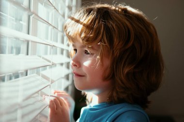 Karantina konsepti. Koru kendini. Evde tek başına kal. COVID-19 tecrit. Pencereden bakan çocuk. Koronavirüs salgını