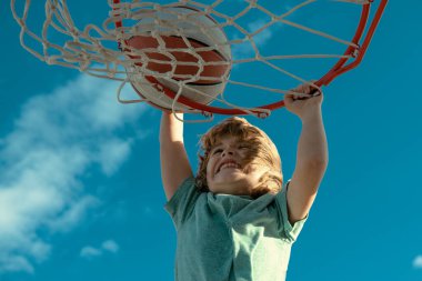 Çocuk basketbolcu smaç basıyor. Aktif çocuklar basketbolla açık havada eğleniyorlar.