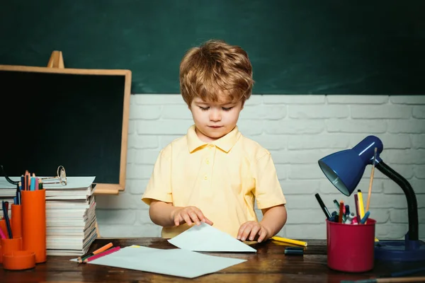 学校に戻る 机の近くで学校用品と幸せな表情をした小さな男の子の生徒 学校のコンセプト — ストック写真