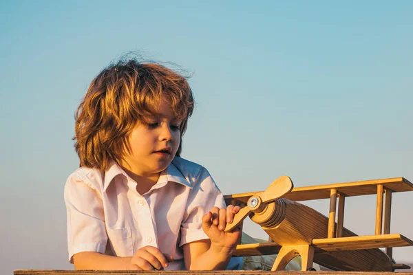 木製のおもちゃの飛行機で遊んでいる子供の男の子 パイロットになる夢 子供たちの夢 木製の飛行機と子供パイロットアビエイター — ストック写真