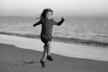 Deniz kıyısına yakın sularda koşan bir çocuk. Bir çocuk deniz kıyısında koşuyor. Çocukların geri kalanı yaz tatilinde. Çocukla yaz tatili