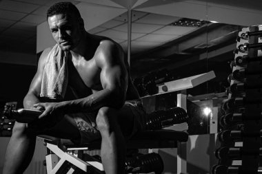 Sporcu antrenmandan sonra dinleniyor. Spor salonundaki adam. Çıplak gövdeli sportif bir erkek. Antrenman adamı. Güçlü atletik vücut