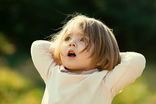日当たりの良い夏の夜に畑に草の中の驚きの子供の女の子 感情的な赤ん坊の顔 — ストック写真