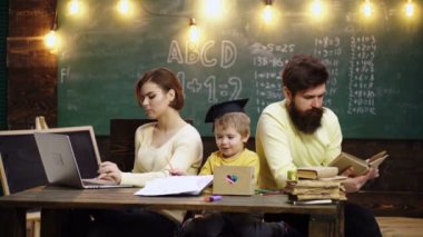 Baba ve anne sevgili oğluna resim çizmeyi ve resim yapmayı öğretiyor. Çocukların öğrenme ve eğitim konsepti. Mutlu bir aile. Anne baba ve oğul birlikte okuyorlar. İlkokuldan bir çocuk.