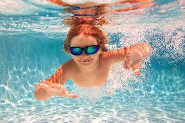 Çocuk su altında havuzda yüzüyor. Çocuk denizde su altında yüzer. Çocuk yüzme havuzunda oynuyor ve dalıyor. Komik çocuklar denizde ya da havuzda yüzer. Yaz tatili kavramı