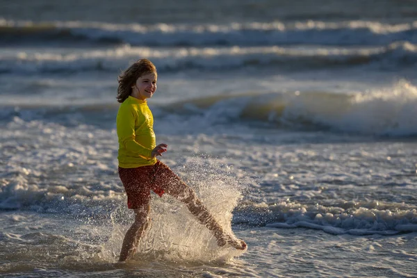夏休みの間 水着姿の子供が海の水の中に走ります 海沿いを走る子供 夏のビーチで子供 子供は海の水でレースを実行します 海の波に沿って水で走る子供 夏休み — ストック写真