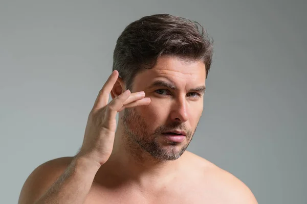 Close-up portrait of perfect brunet man touching chin and skin. Handsome man touching face in gray studio isolated background. Perfect skin. Man cosmetic, skin treatment. Hygiene skin care male face