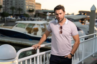 Moda mankeni, şık polo takımında şehirde yürüyor. Adam sokakta yürüyor. Şehirde yürüyen caddedeki moda adamı. Dışarıdaki şık yakışıklı adamın portresi. Çekici bir adamın portresi