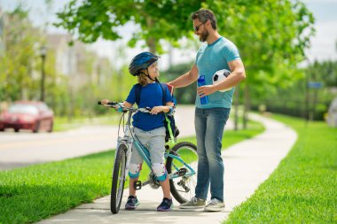 Babalar günün kutlu olsun. Mutlu aile, erkek nesiller. Arkadaş canlısı aile ve yaz yaşam tarzı kavramı. Baba ve oğul Amerikan mahallesinde bisiklet sürüyor. Ebeveynler ve çocuklar arkadaş. Önce çocuk bisikleti