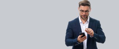 Resmi takım elbiseli Avrupalı iş adamı cep telefonundan izliyor. Resmi giyinen yakışıklı adam akıllı telefon kullanıyor, SMS mesajı yazıyor. Başlık için afiş, kopyalama alanı. Web tasarımı için poster