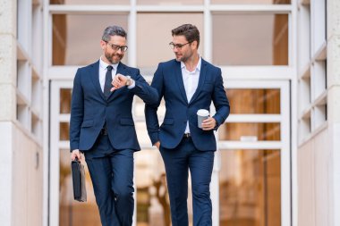 İki iş adamı. İki iş adamı takımı için pazarlama stratejisi. Ticari satış stratejisi gelirde etkiliydi. Takım elbiseli bir adam Amerikan ofisinin önünde yürüyor.