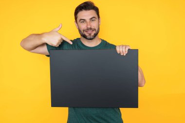 Boş afişi olan orta yaşlı bir adam. Metnin ya da tasarımın için kopyalama alanı gösteriliyor. Stüdyo arka planında boş reklam panosu gösteren bir adam. Boş pano, reklam tabelası.