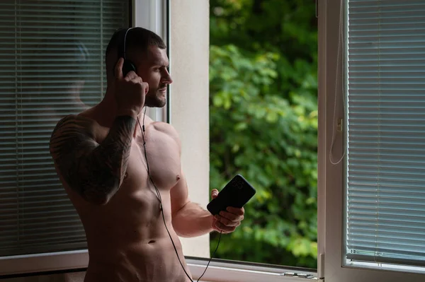 Sexy Nahý Mladý Muž Telefonem Poslech Hudby Sluchátka Obývacím Pokoji — Stock fotografie