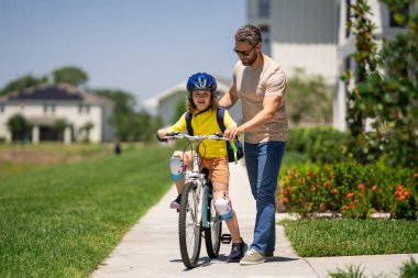 Babalar Günün kutlu olsun. Kask süren bisikletli baba ve oğul. Babasıyla bisiklet süren kasklı, sevimli, beyaz bir çocuk. Aile açık hava yaz aktiviteleri. Babalar sever